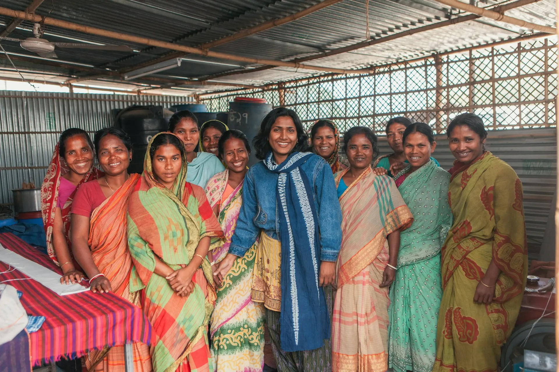 A women's collective smiling together inside their workshop space